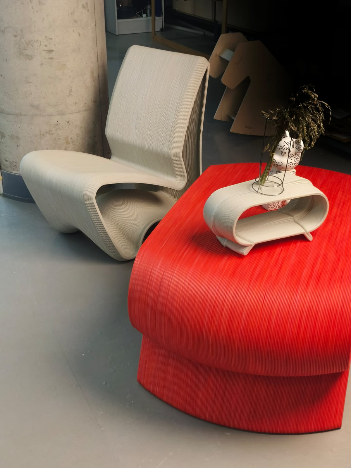 Custom 3D printed chair and red table with curved surfaces.png