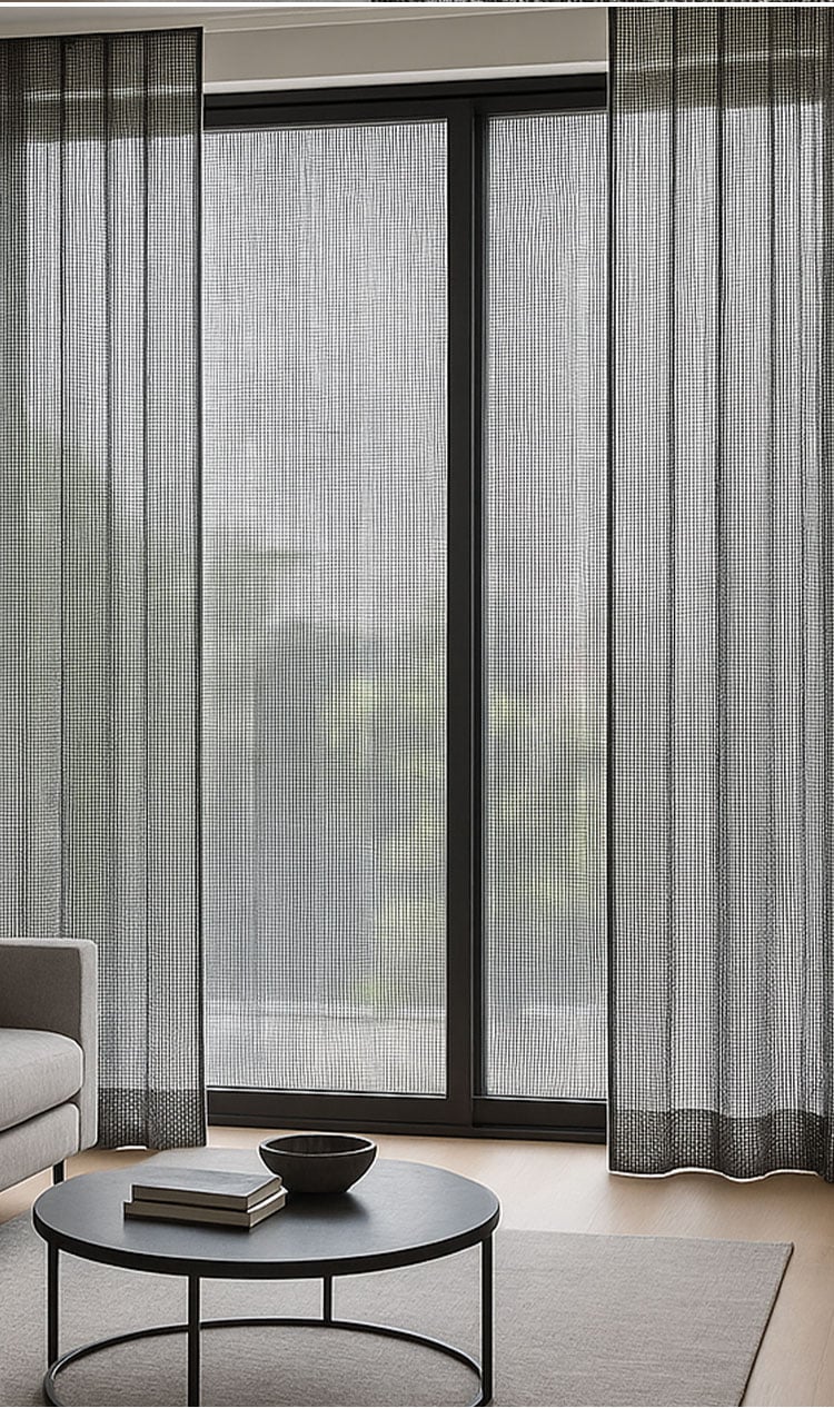 Minimal living space with white sheer curtains, gentle daylight diffusion, floor lamp, and warm wood flooring.