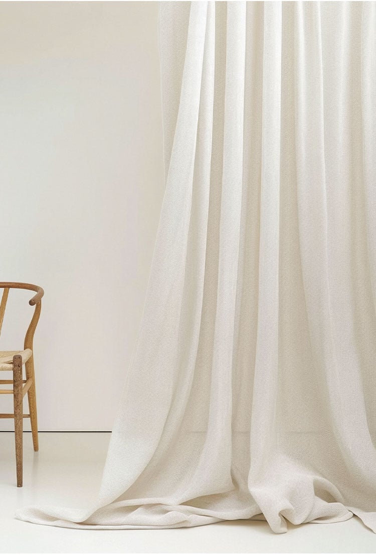 Minimal studio scene with heavy-denier slub sheer curtain fabric pooling on the floor, showing natural drape and textured surface.