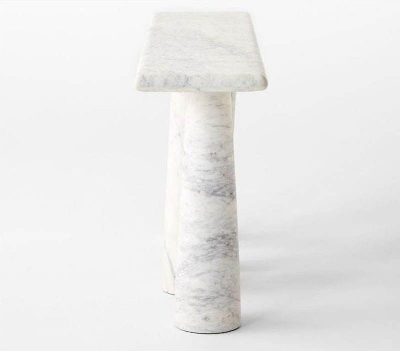 Narrow marble console table behind couch against wall