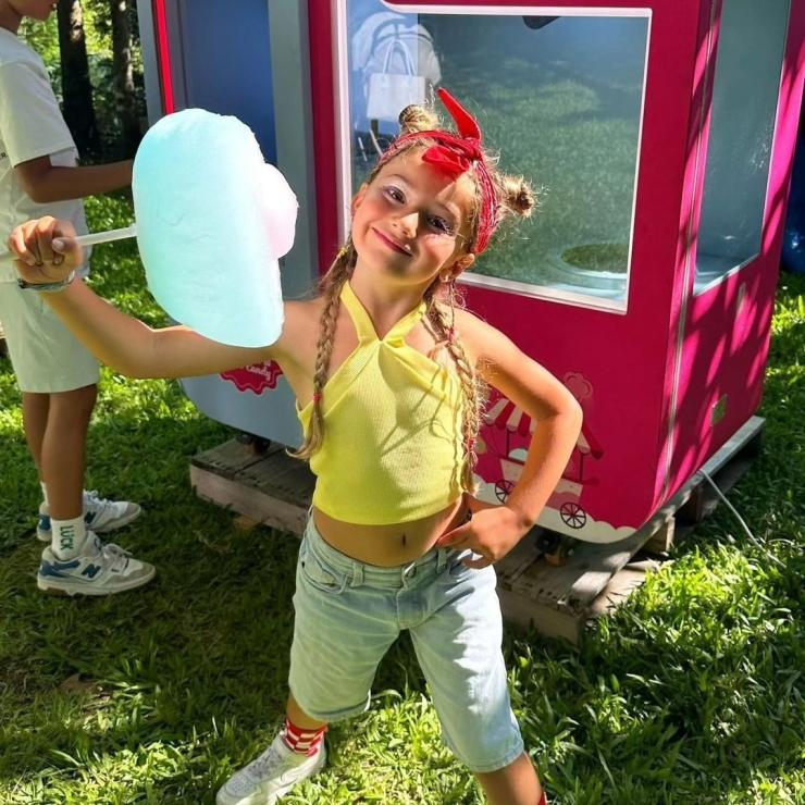 A child enjoying a cotton candy from the cotton candy vending machine in the theme park.png