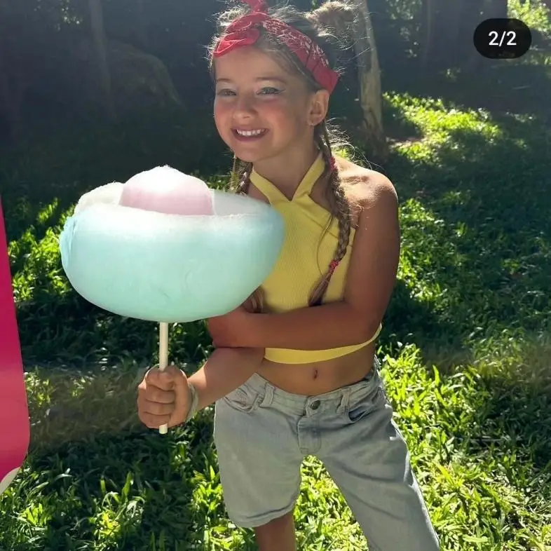 A child holding a cotton candy with a big smile on her face.webp
